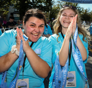Happy looking volunteers clap while holding medals to give to runners