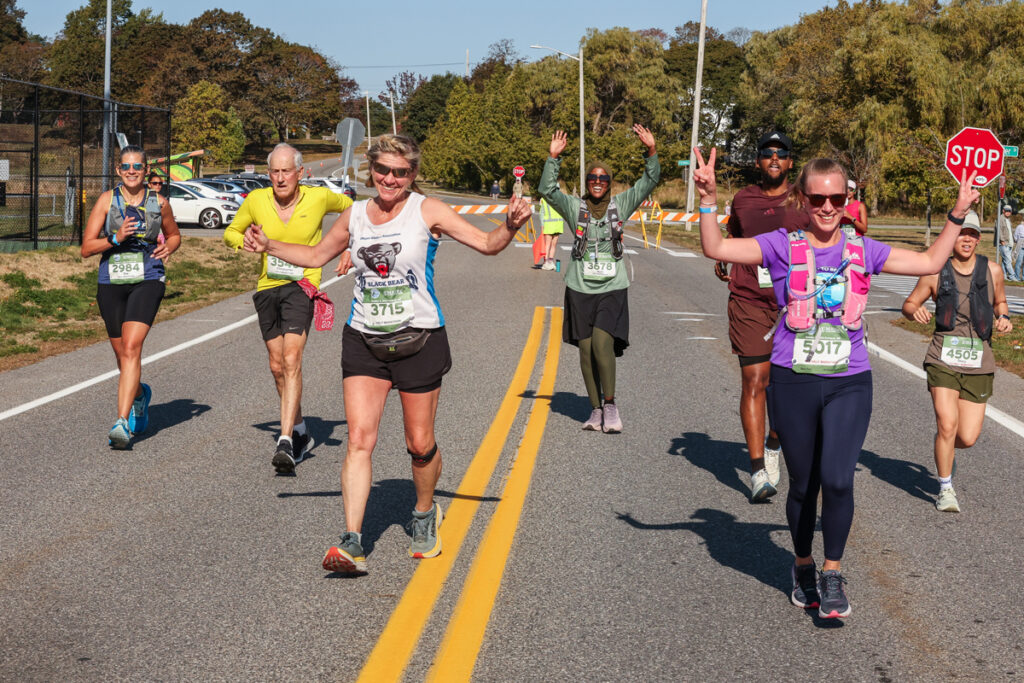Group of runners smile and wave on the course