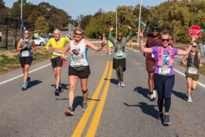 Group of runners smile and wave on the course